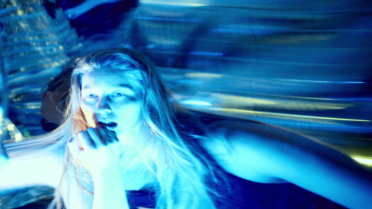 Woman Expressing Intense Emotion beside Distorting Mirror in Neon Lights