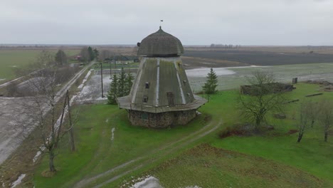 Schöne-Luftaufnahme-Der-Alten-Hölzernen-Windmühle-In-Der-Mitte-Des-Feldes,-Prenclavu-windmühle,-Bewölkter-Wintertag,-Breite-Drohne,-Die-Sich-Rückwärts-Bewegt