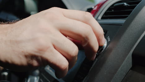mano masculina ajusta la afinación de la toma de primer plano de la radio del coche