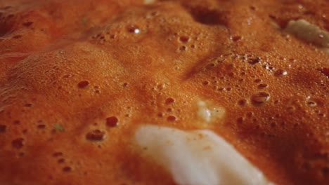 extreme close up of simmering bubbles in hot tomato stew soup with chicken pieces