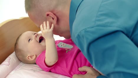 cu young father plays with a little sweet daughter who lies on a changing table