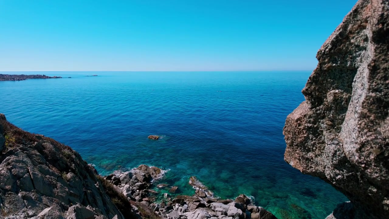 Splendida vista dall'alto delle ripide scogliere di granito e delle acque cristalline e blu del Mediterraneo a Capo Carbonara, Sardegna. Autentico paesaggio costiero per contenuti di viaggio e benessere