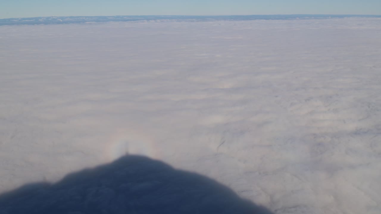 Mountain shadow reflecting on the cloud cover with rainbow