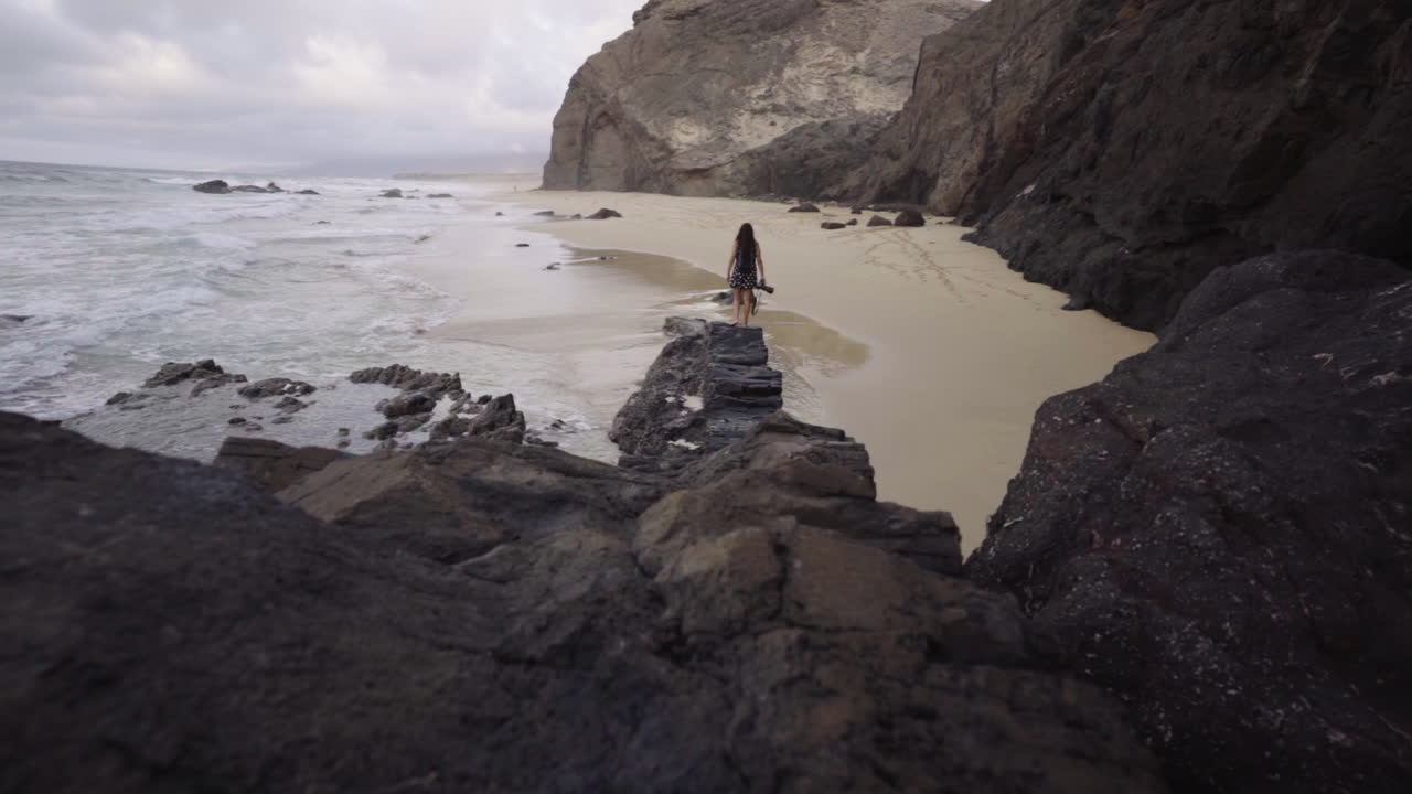 fotógrafo profesional independiente parado en la cima del acantilado de roca oceánica en fuerteventura, isla canaria, españa