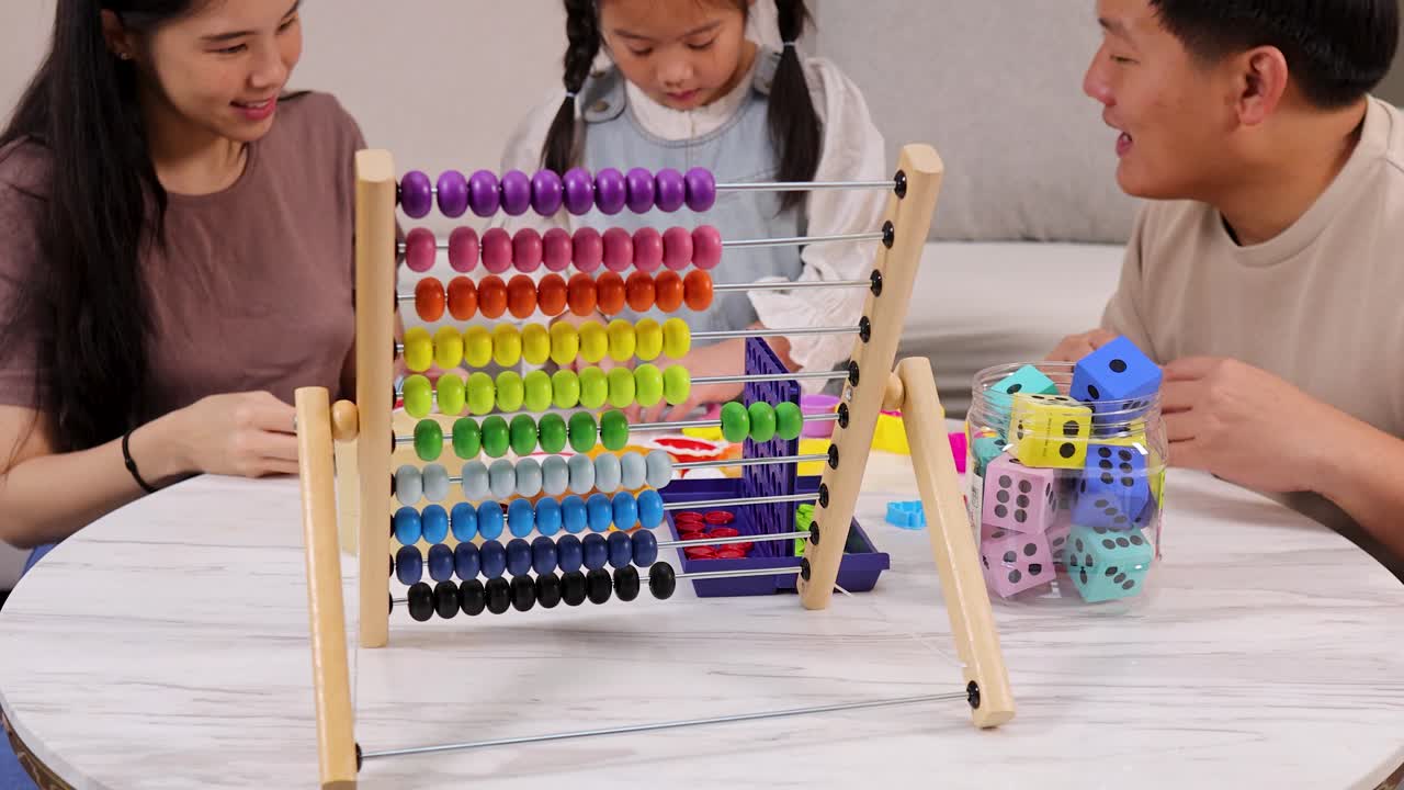 Asian parents and young daughter play with educational toys and abacus in bright living room