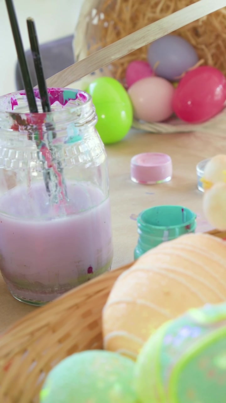 Vertical video: Panning camera showing pastel eggs and brushes in purple jar for Easter decor
