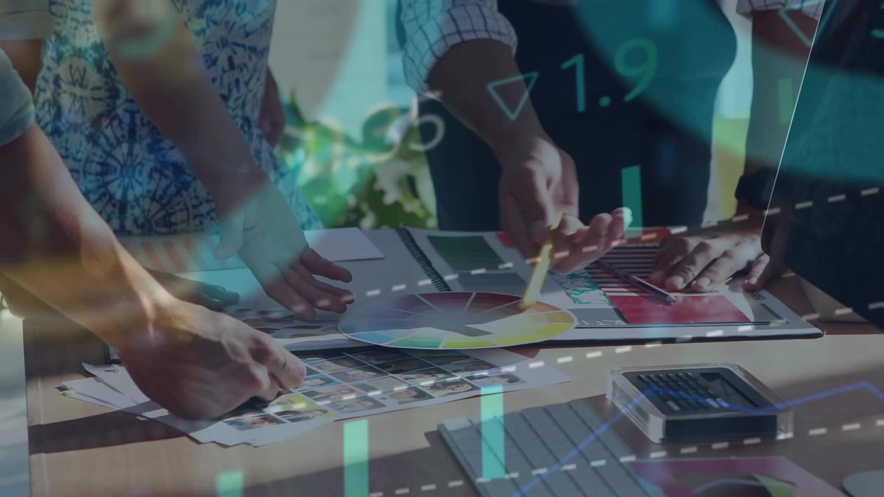 Design pros leaning over table spreading prints rotating color wheel showing graphs aligning swatch