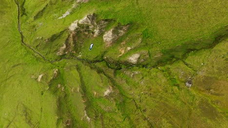 Amplia-Toma-Aérea-Estática-A-Vista-De-Pájaro-De-Un-Lanzamiento-De-Parapente-Desde-Un-Acantilado-Y-Navegar-Sobre-Hierba-Verde-Brillante-Y-Barrancos-Rocosos