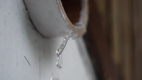 Fresh-rain-water-dripping-out-of-raised-white-drain-pipe-gutter-in-Indonesia,-Asia-during-heavy-storm