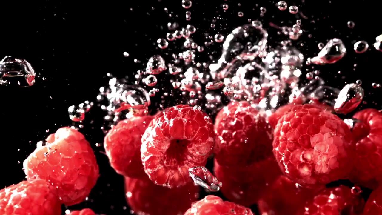 Fresh Red Raspberries Falling into Water in Slow Motion