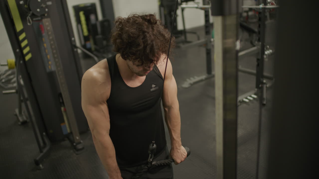 Muscular Man Performing Triceps Pushdowns on Cable Machine in Gym