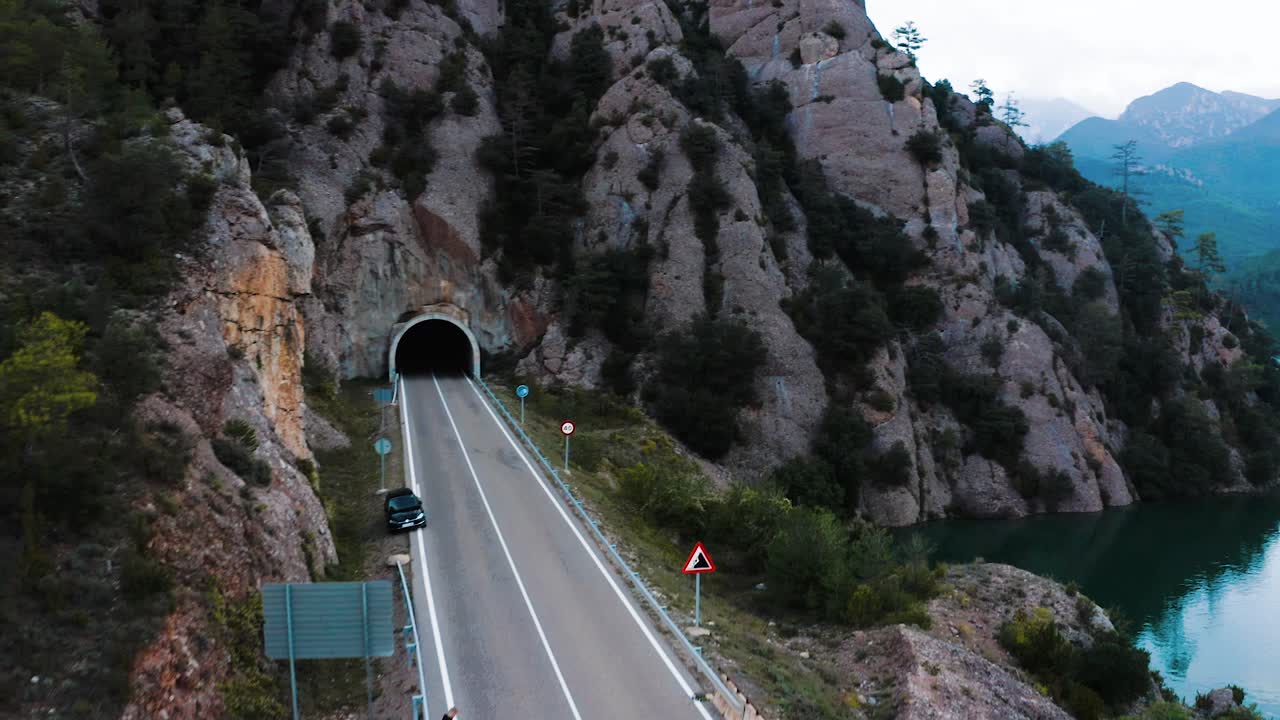 Person Walking on Bridge Towards Tunnel with Mountain and Lake View