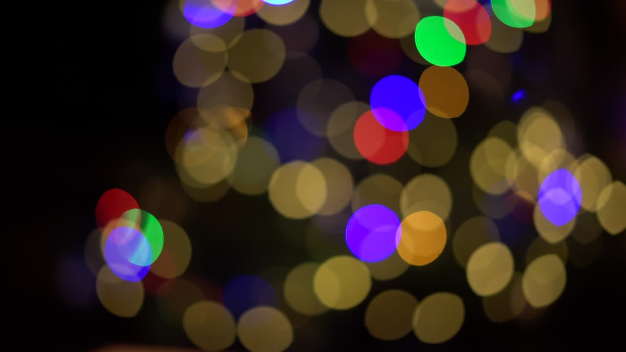 Panorâmica através de luzes de Natal festivas e borradas. Fundo colorido de bolas bokeh desfocadas