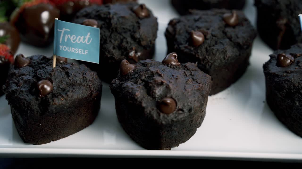 Ripresa rotante di uno stuzzicadenti inserito su muffin di barbabietola al cioccolato e fragole ricoperte di cioccolato per dolcetti a forma di cuore per San Valentino.
