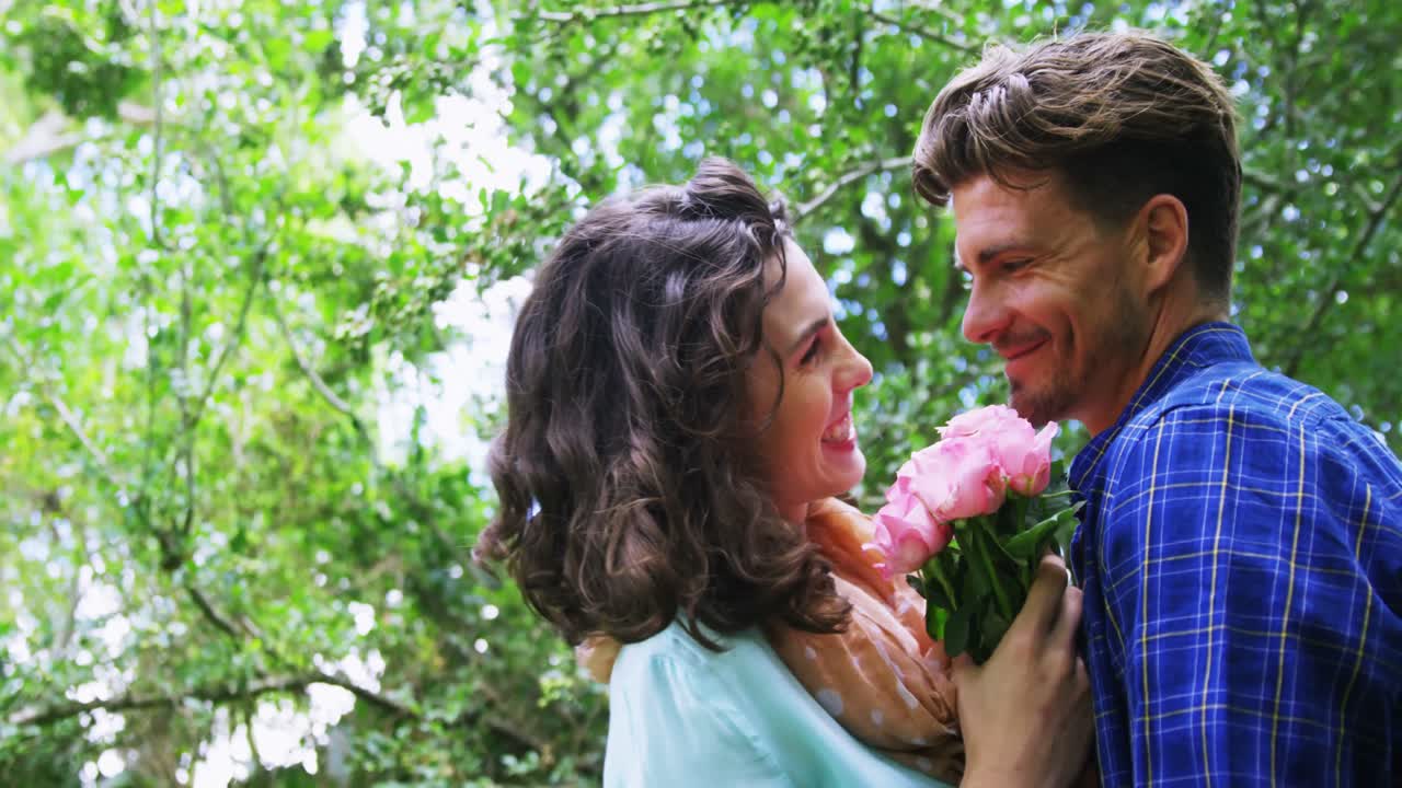 pareja romántica sosteniendo un ramo de flores en el jardín