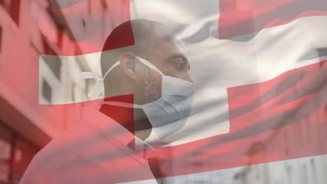 animation of flag of switzerland waving over man wearing face mask during covid 19 pandemic