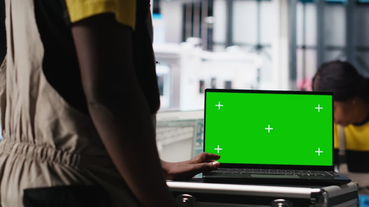 Black man adjusting robotic machinery settings through chroma key screen