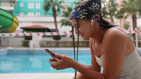 joven usando un teléfono inteligente junto a la piscina