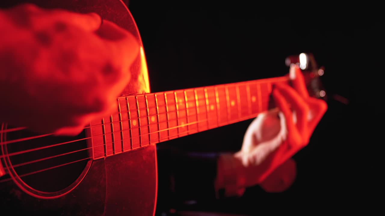 Playing an Acoustic Guitar with Red Backlight and Black Background
