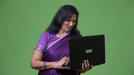 mature happy beautiful indian woman smiling while using laptop