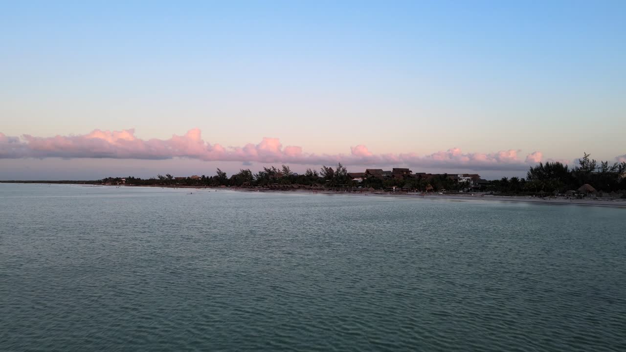 Vidvinkel droneoptagelse under solnedgang med smukke lyserøde nuancer i skyerne, beliggende på den tropiske ø Holbox i Det Caribiske Hav i Mexico, optaget i 4k