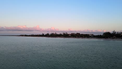 Wide-angle-drone-shot-during-sunset-with-beautiful-pink-hues-in-the-clouds-located-on-the-tropical-island-of-Holbox-in-the-Caribbean-sea-in-Mexico-shot-in-4k