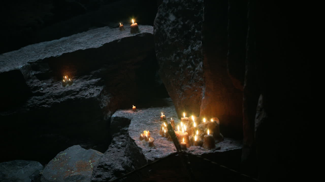 Candles illuminated in a dark cave setting create a mystical atmosphere