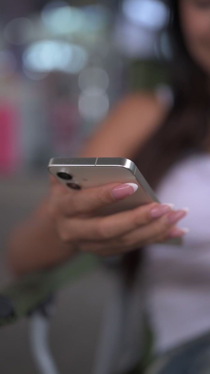 Primo piano della mano di una donna che usa uno smartphone, filmato verticale