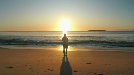 woman stands alone at the beach looking at the ocean