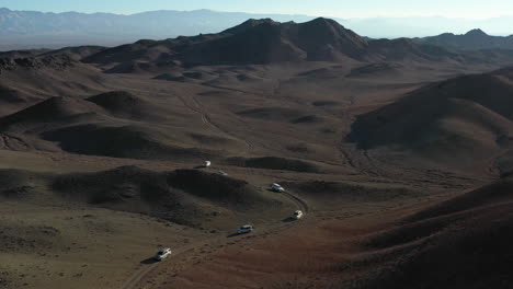 Revealing-drone-shot-of-a-fleet-of-cars-caravanning-in-the-Charyn-Canyon,-Kazakhstan