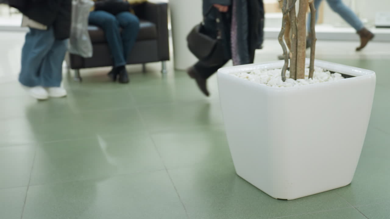 쇼핑몰에 있는 색 꽃병, 배경에는 의자에 앉아 있는 사람. 영상은 쇼핑몰의 조용하고 조직적인 환경을 포착합니다. 휴대용 카메라로 찍은 영상입니다.