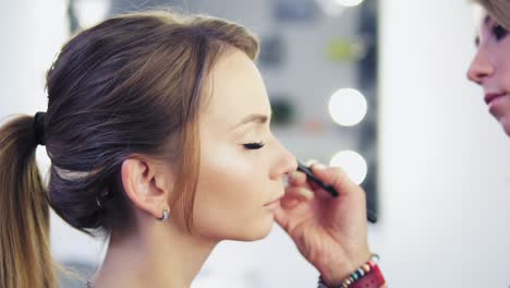 Vista-De-Cerca-Del-Maquillador-Aplicando-Sombra-De-Ojos-En-El-Párpado-Con-Una-Brocha-De-Maquillaje.-Maquillaje-Profesional.-Tiro-En-Cámara-Lenta