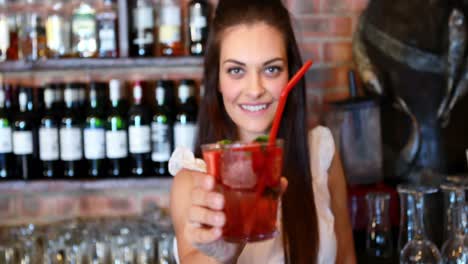 Portrait-of-barmaid-serving-cocktail-at-bar-counter