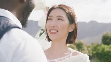 video of happy diverse bride and groom smiling at each other at outdoor wedding