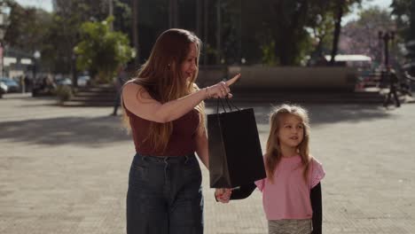 mother and daughter walking hand-in-hand in a park