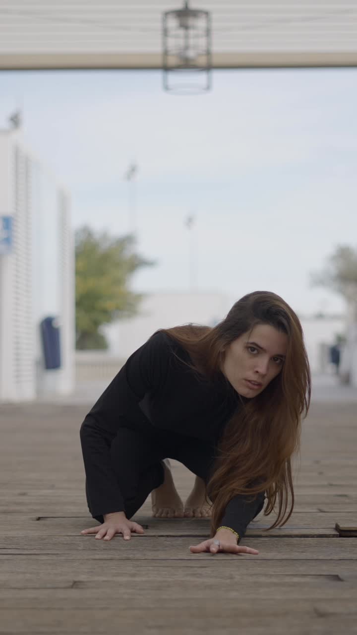 Woman in Black Crouching on a Wooden Boardwalk