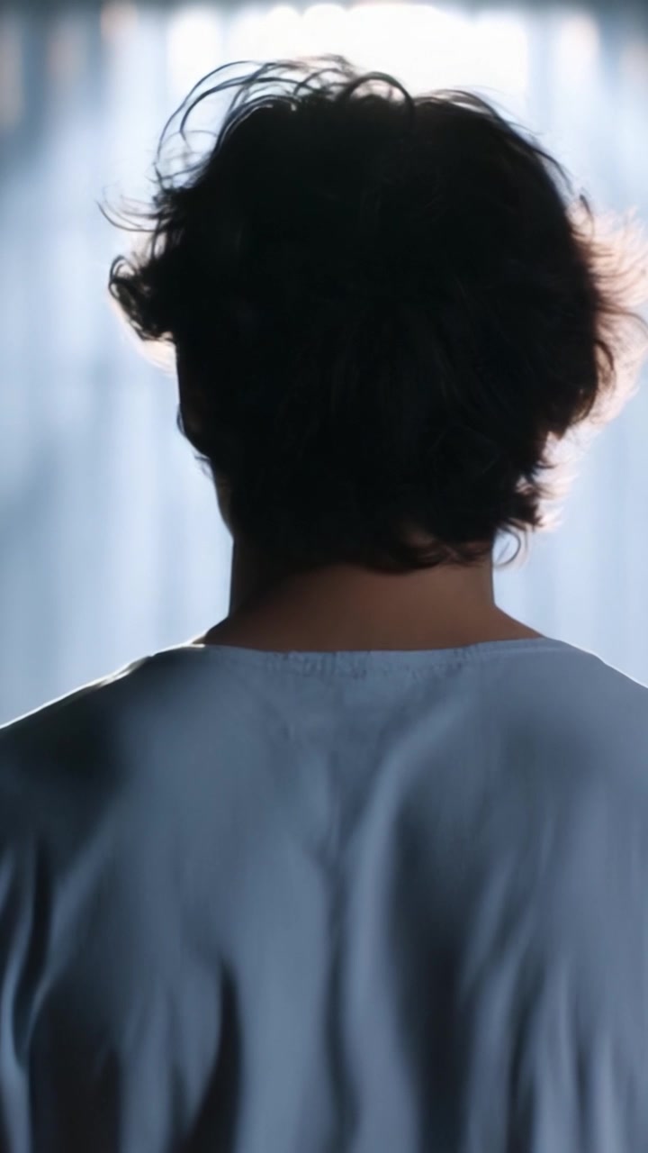 A Reflective Moment: An Individual Contemplates Life from a Back View Illuminated by Soft Light Filtering Through Drapes