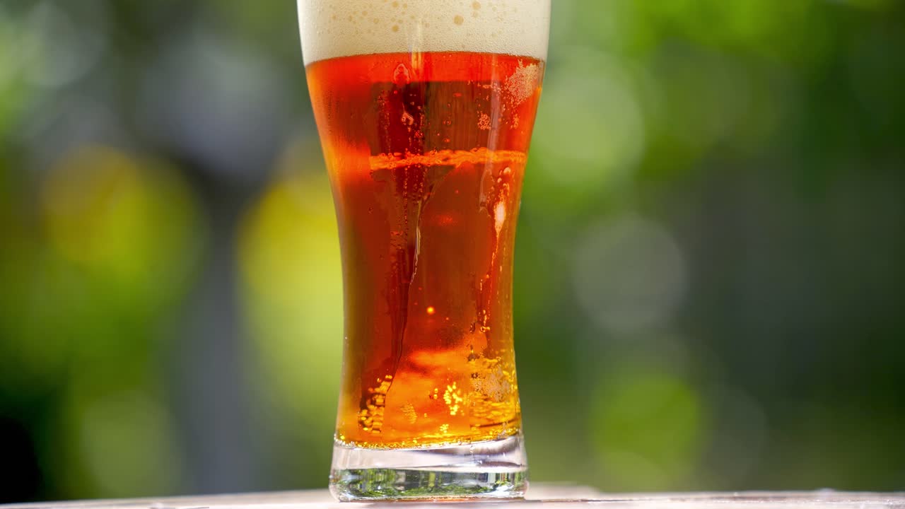 Fresh beer with bubbles in glass. Cold brewed drink in a glass with water drops over blur background. Craft beer close up.