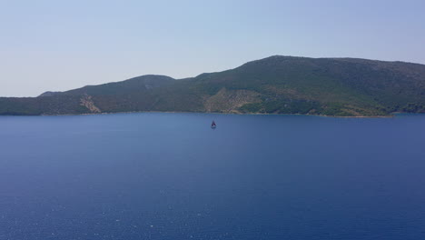 Aerial:-A-sailboat-with-red-sails-is-sailing-offshore-on-a-clear-summer-day