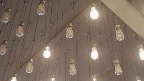 beautiful light bulbs in large numbers illuminate a large room. the light bulbs are arranged in even rows.