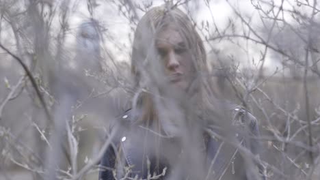 woman in a black jacket amidst branches