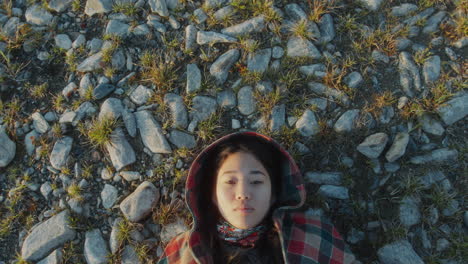 top down of young asian woman lying on rocky ground outdoors