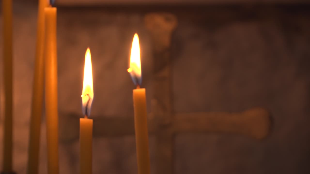 Primo piano di candele accese e una croce di metallo in una cappella ortodossa bulgara. Chiesa Ortodossa Orientale. Cambio di messa a fuoco. Messa a fuoco selettiva. Concetto