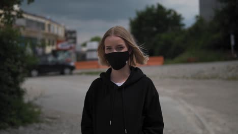 portrait of a young blonde female with face mask in exterior looking at camera