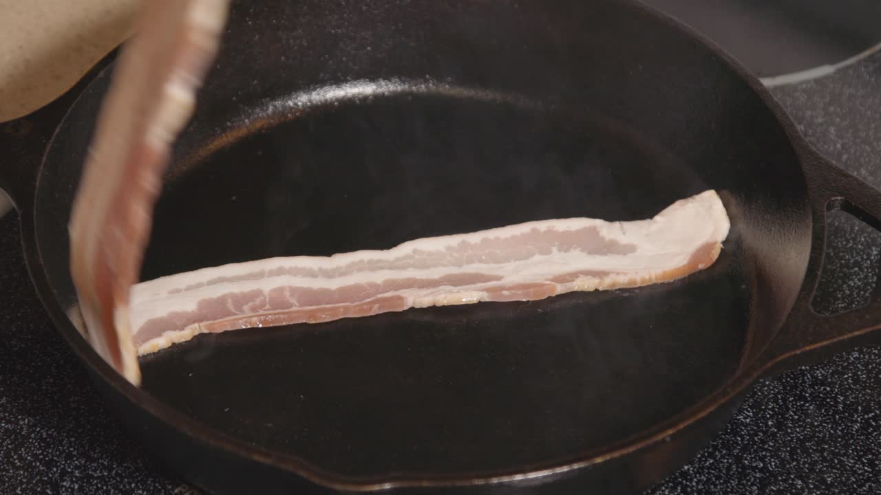 스토브에 있는 주철 팬 튀김 베이컨 생 베이컨 팬에 들어가는