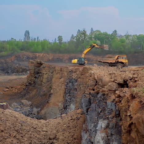 tractor bucket is filling a truck. industrial excavator loading soil on a truck on nature background. earth moving equipment.