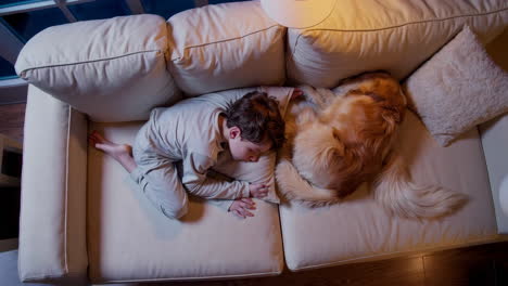boy and golden retriever sleeping on couch