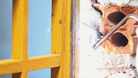 plano medio de un trabajador soldando metal en un marco de ventana