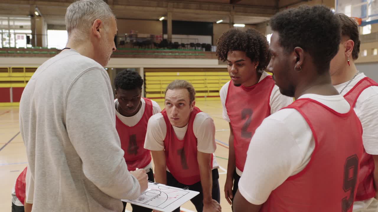 Basketballteam bespricht sich mit Trainer, der die Strategie erklärt