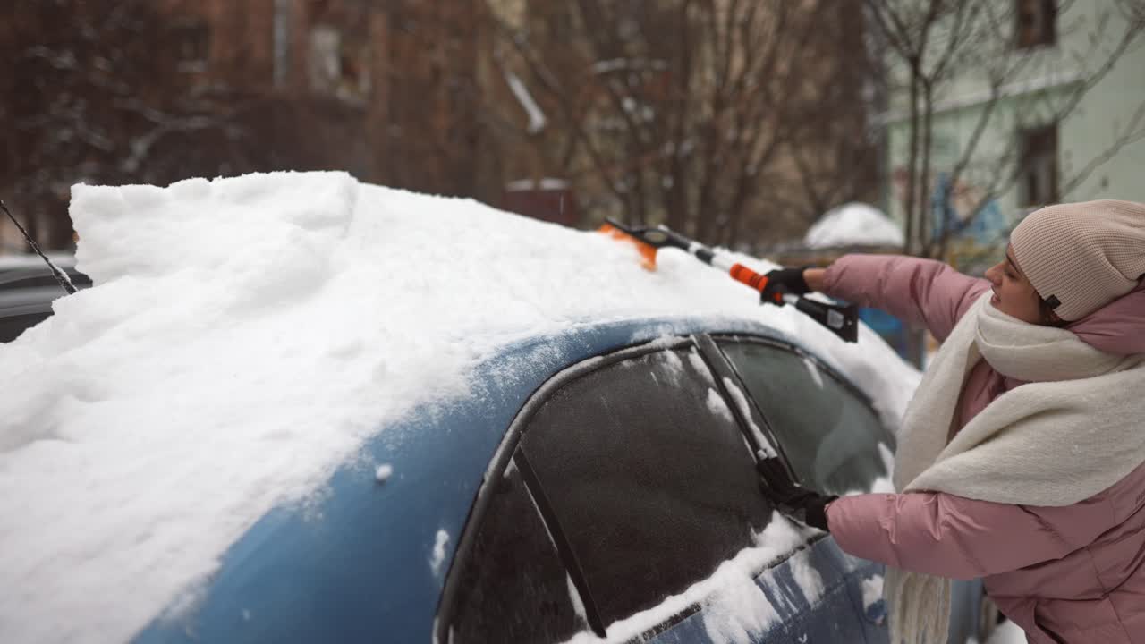 여자 가 차 에서 눈 을 제거 하고 있다